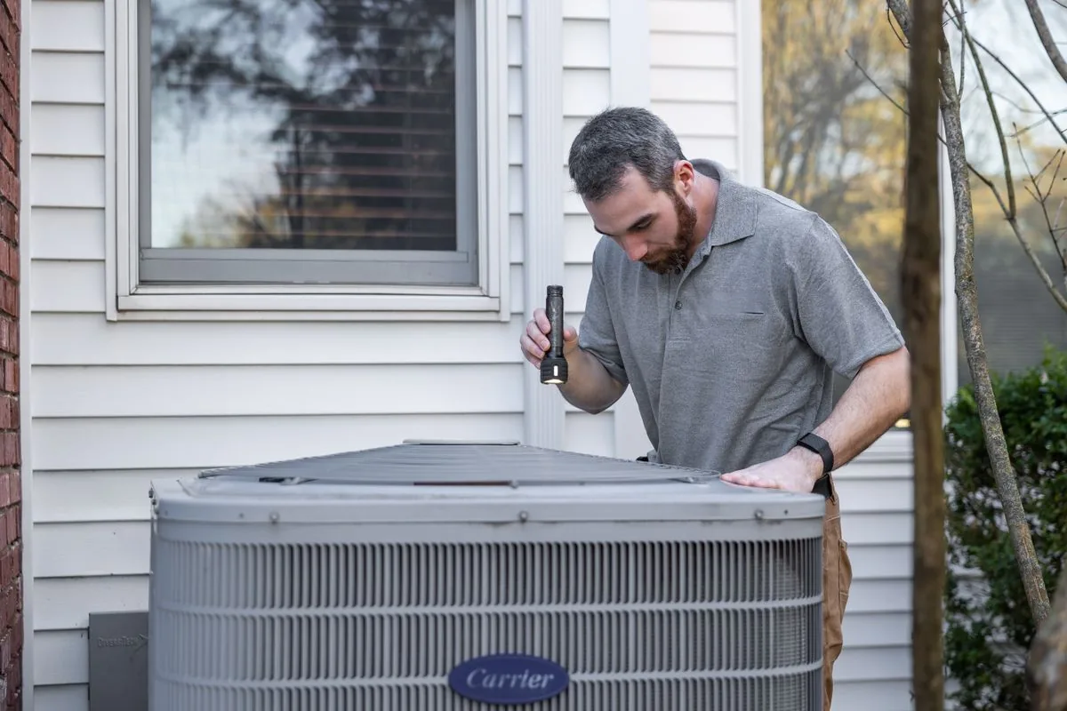 HVAC technician inspecting a condenser unit